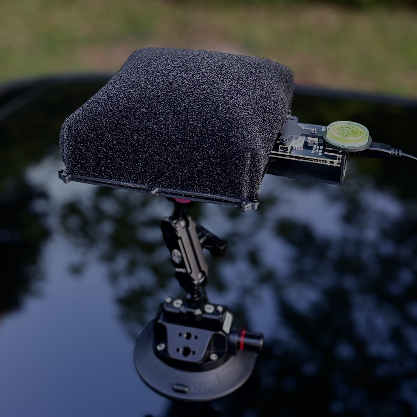The Falcon acoustic array head: a foam-covered microphone panel on an articulated suction mount, attached to a vehicle roof.